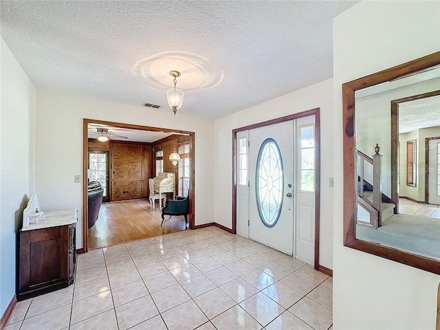 tiled entryway with a textured ceiling and ceiling fan