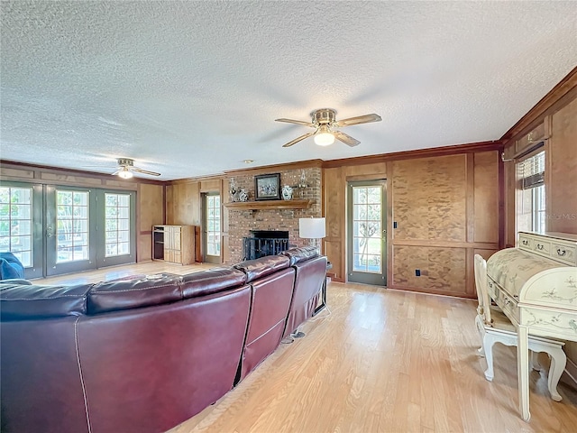 living room featuring a brick fireplace, crown molding, a textured ceiling, and light hardwood / wood-style flooring