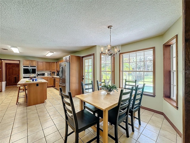 dining area with light tile patterned floors, a textured ceiling, and an inviting chandelier