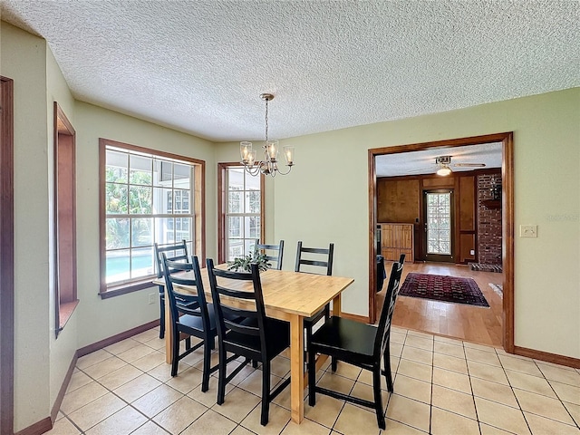 dining area with a textured ceiling, ceiling fan with notable chandelier, and light hardwood / wood-style flooring