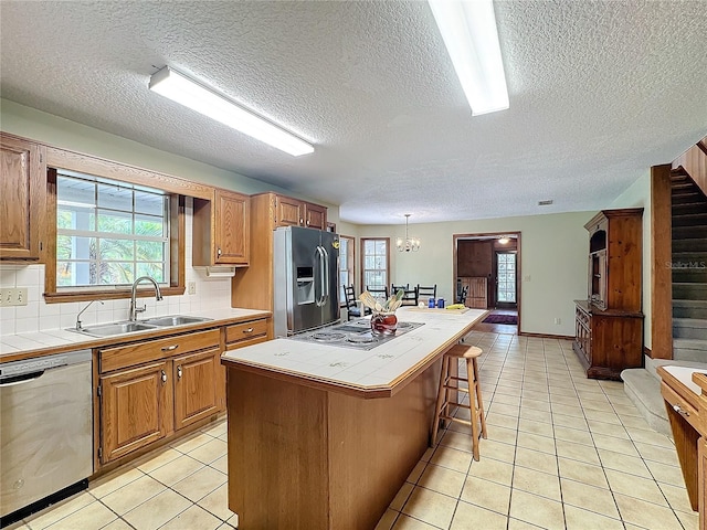 kitchen with tile countertops, stainless steel appliances, a kitchen island, and a wealth of natural light