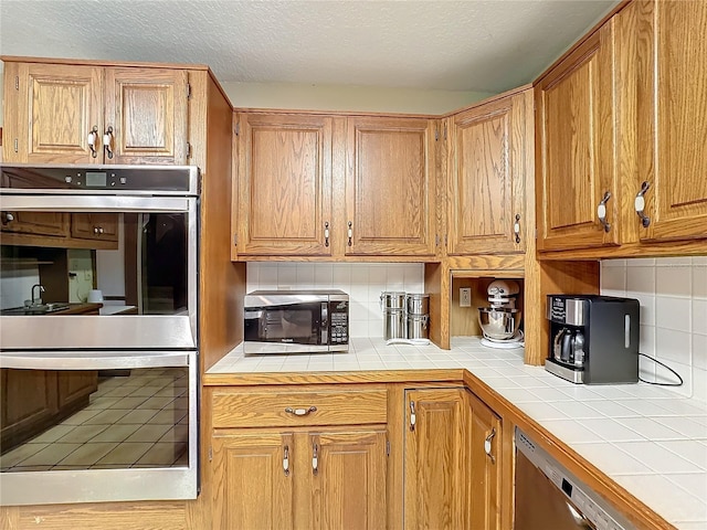 kitchen with decorative backsplash, appliances with stainless steel finishes, and tile counters