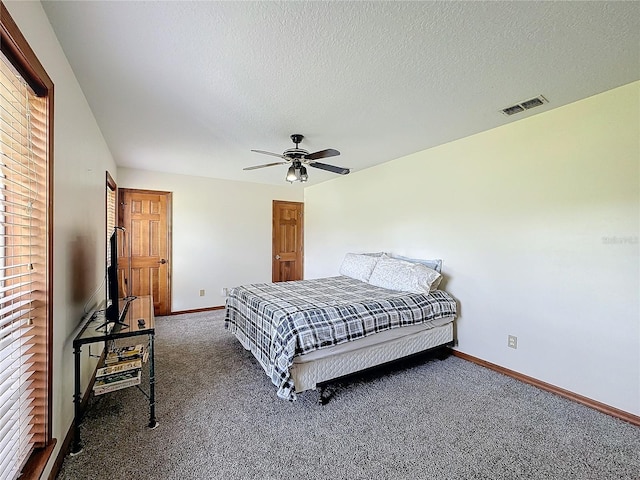 bedroom with dark colored carpet, a textured ceiling, and ceiling fan