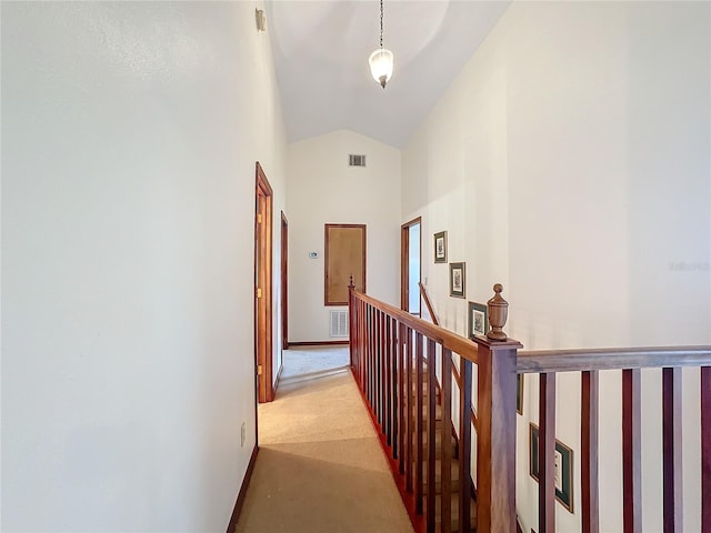 hallway with light colored carpet and high vaulted ceiling