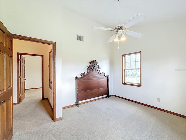 bedroom featuring ceiling fan, light colored carpet, and a high ceiling