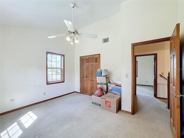 unfurnished bedroom with light colored carpet, high vaulted ceiling, and ceiling fan