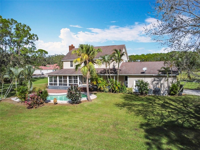 back of house featuring a lawn and a sunroom