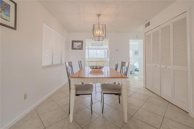 dining room featuring a textured ceiling, a notable chandelier, and light tile patterned floors