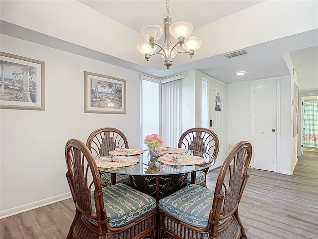 dining area with hardwood / wood-style flooring and a notable chandelier