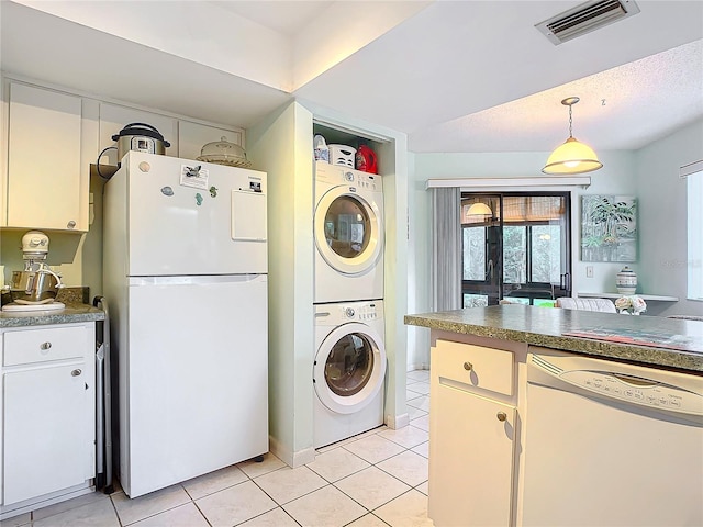 clothes washing area featuring a textured ceiling, light tile patterned flooring, and stacked washer and clothes dryer