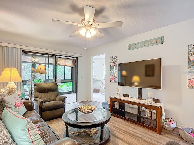 living room with a textured ceiling, light hardwood / wood-style floors, and ceiling fan