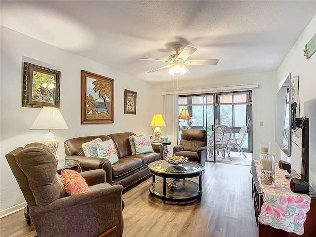 living room with ceiling fan, wood-type flooring, and a textured ceiling