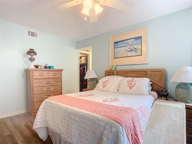 bedroom featuring dark wood-type flooring, ceiling fan, a closet, and a spacious closet