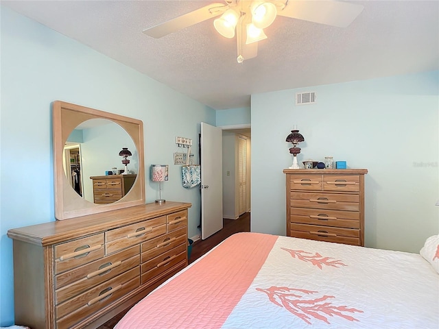 bedroom featuring dark hardwood / wood-style floors, ceiling fan, and a textured ceiling