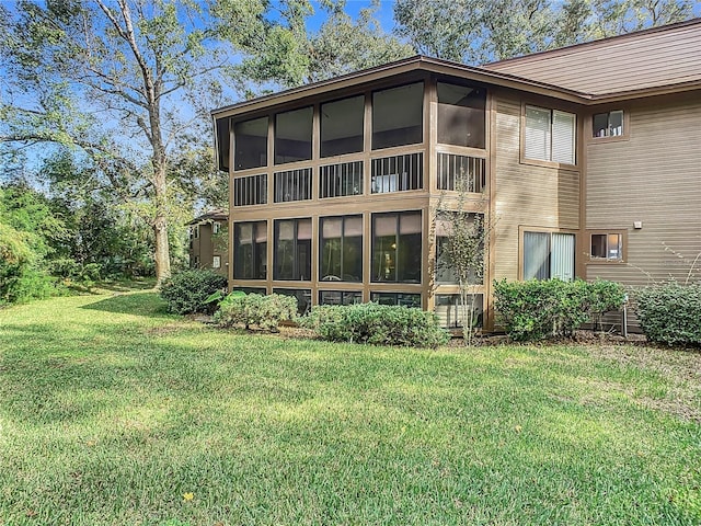 back of property featuring a lawn and a sunroom