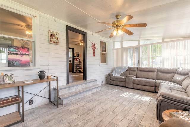 living room with lofted ceiling, light hardwood / wood-style flooring, ceiling fan, and wooden walls