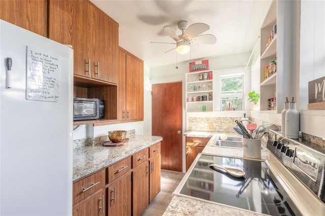 kitchen featuring ceiling fan, sink, white fridge, light hardwood / wood-style floors, and stainless steel range with electric cooktop