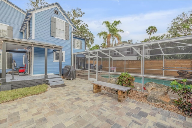 back of house featuring a lanai, a swimming pool with hot tub, and a patio