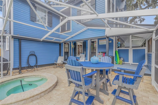 view of patio with glass enclosure and an in ground hot tub