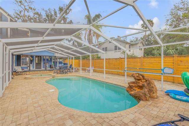 view of swimming pool featuring glass enclosure, a patio, and an in ground hot tub