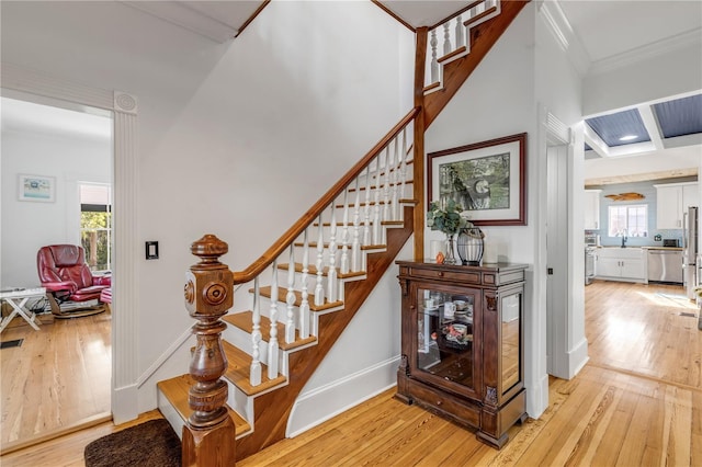 stairs with hardwood / wood-style floors, a healthy amount of sunlight, crown molding, and sink