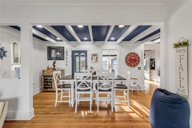 dining space featuring ornamental molding, light wood-type flooring, and beamed ceiling