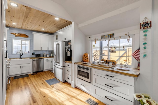 kitchen with butcher block counters, light hardwood / wood-style floors, white cabinetry, and stainless steel appliances