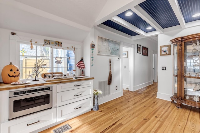 kitchen featuring stainless steel oven, white cabinetry, butcher block countertops, and light hardwood / wood-style floors