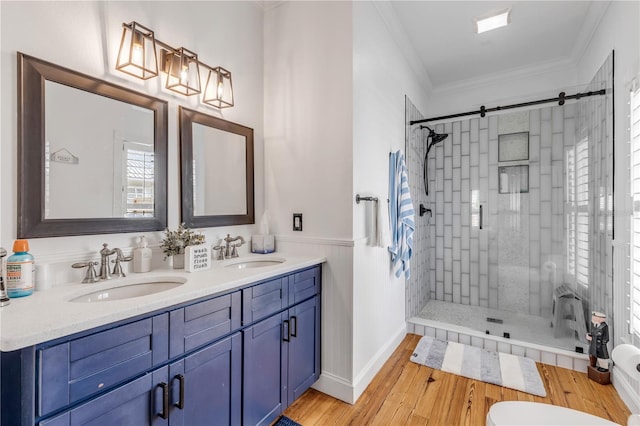 bathroom with tiled shower, wood-type flooring, crown molding, and vanity