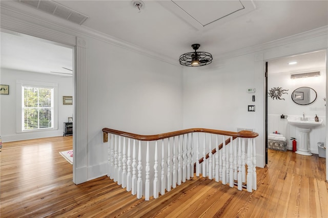 stairway featuring hardwood / wood-style floors, sink, and ornamental molding