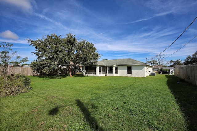 back of property featuring central AC and a yard