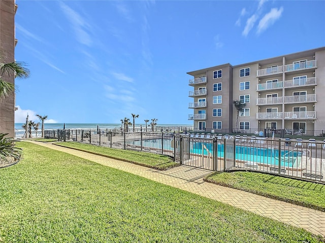 view of swimming pool with a water view and a lawn