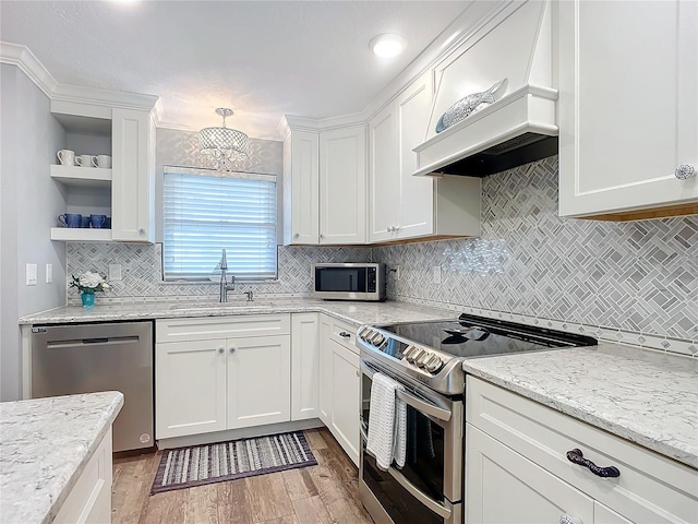 kitchen featuring light stone counters, custom exhaust hood, stainless steel appliances, sink, and white cabinets