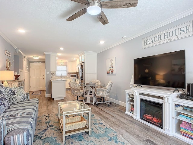 living room with ceiling fan, crown molding, light hardwood / wood-style floors, and a textured ceiling