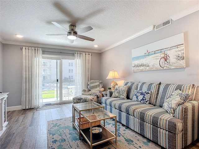 living room with a textured ceiling, hardwood / wood-style flooring, ceiling fan, and crown molding