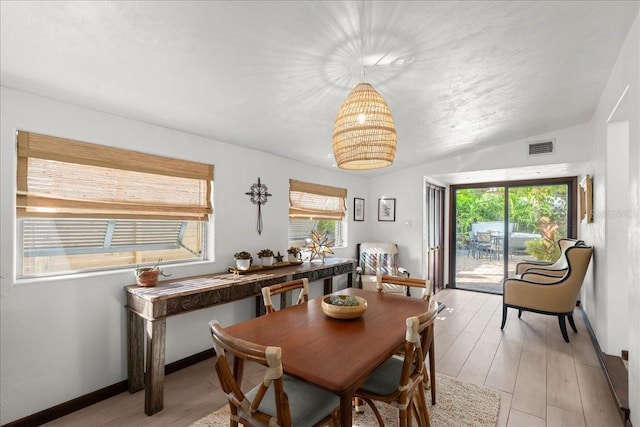 dining space with light wood-type flooring and vaulted ceiling
