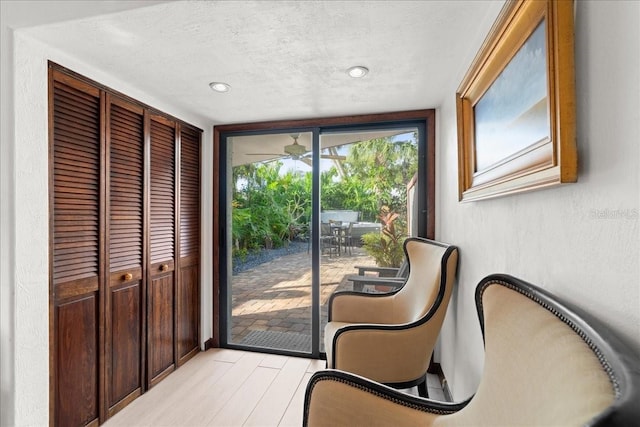 sitting room featuring a textured ceiling, light hardwood / wood-style flooring, and ceiling fan