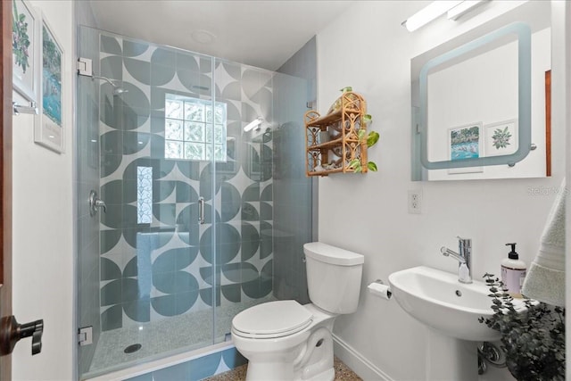 bathroom featuring sink, a shower with shower door, and toilet