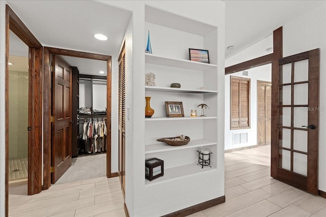 hallway with light hardwood / wood-style floors, built in features, and french doors