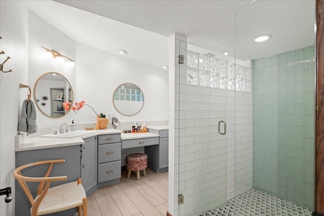 bathroom with vanity, a shower with door, and a textured ceiling