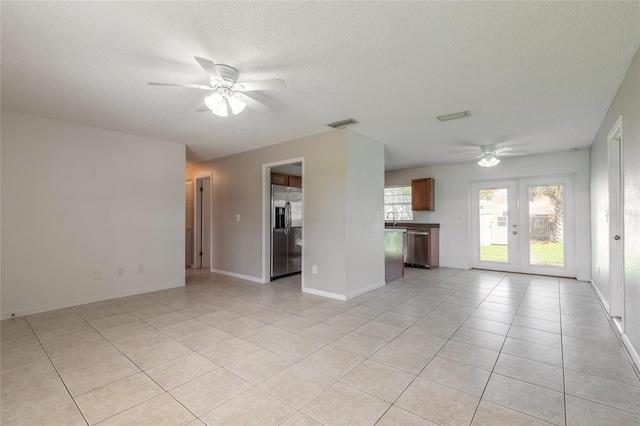 unfurnished living room featuring a textured ceiling, french doors, ceiling fan, and light tile patterned floors