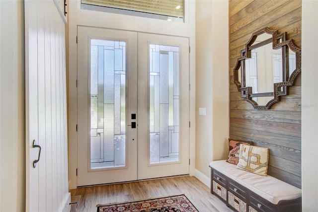 doorway featuring french doors, light hardwood / wood-style floors, and wooden walls