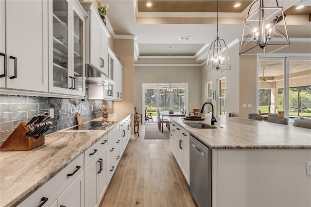 kitchen featuring white cabinetry, sink, stainless steel dishwasher, black electric cooktop, and a kitchen island with sink