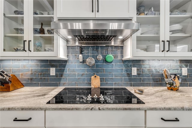 kitchen featuring white cabinets, wall chimney exhaust hood, black electric stovetop, and tasteful backsplash