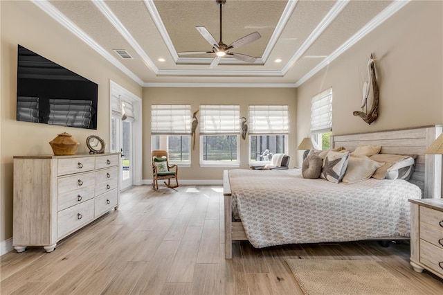 bedroom with ceiling fan, a textured ceiling, a raised ceiling, light hardwood / wood-style flooring, and crown molding