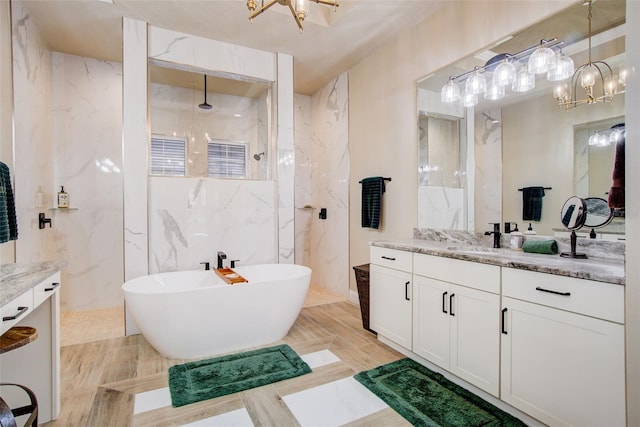 bathroom featuring tile walls, vanity, independent shower and bath, and an inviting chandelier