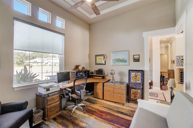 office space featuring a high ceiling, ceiling fan, ornamental molding, and hardwood / wood-style flooring