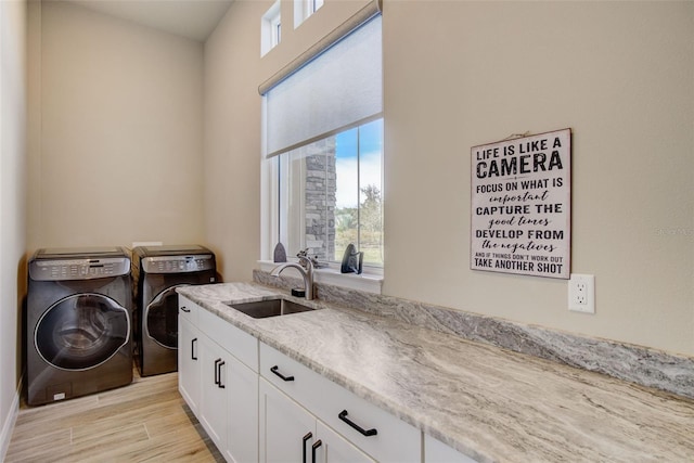 laundry room featuring cabinets, light hardwood / wood-style floors, washing machine and dryer, and sink