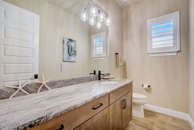 bathroom featuring toilet, vanity, a wealth of natural light, and hardwood / wood-style floors