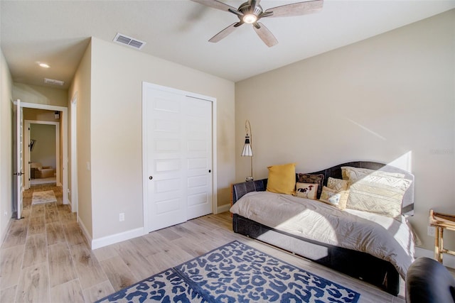 bedroom featuring light hardwood / wood-style floors, ceiling fan, and a closet